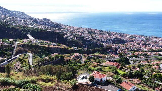Soaring above Madeira coastal city and winding roads