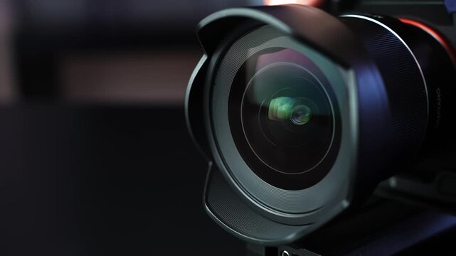 Macro shot of camera lens with hood as aperture slowly opens, revealing shifting reflections in dark studio light with cinematic bokeh&mdash;ideal for filmmaking and tech b-roll.