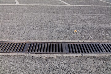 Parking lot rainwater sewer drain grate in Tirana, Albania. Linear stormwater cast iron drain. © Tupungato