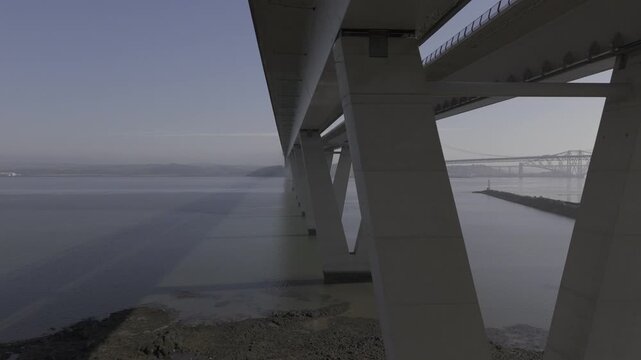 Aerial view of the Forth Bridge, a striking red cantilever railway bridge, contrasting against the calm, grey waters, South Queensferry, United Kingdom.