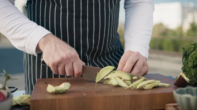 Closeup unrecognizable male chef slicing zucchini, creating thin even cuts, preparing ingredients for cooking, working with focus, ensuring precision alone. Process of cutting vegetables concept