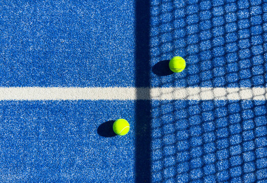 paddle tennis ball near the net on a blue paddle tennis court