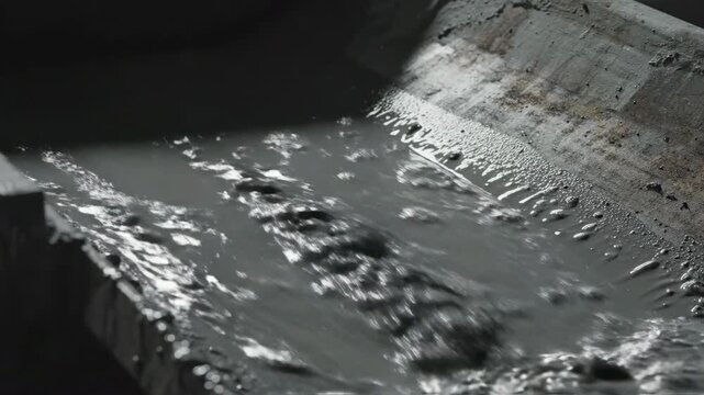 Drilling mud flows through a metal chute in industrial setting