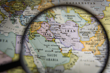 Magnifying glass over a geographical map of the Middle East focusing on Iran and Iraq, geopolitical research and strategic analysis concept