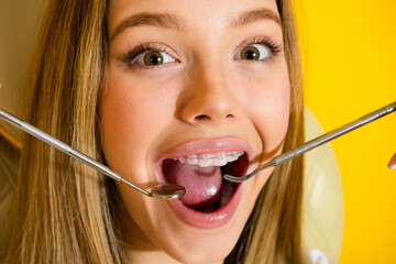 Happy teen girl with braces smiling during dental checkup in a bright yellow clinic setting