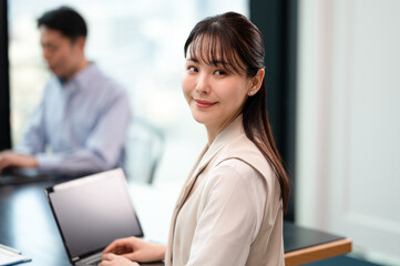 振り向くオフィスでPCを使い笑顔の女性社員