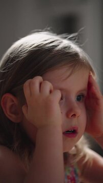 Child watching TV screen. A little girl watches a movie or cartoon very attentively, experiences strong emotions, is scared, worried, and sad. Closeup Scared Face Child Eyes. Vertical video.