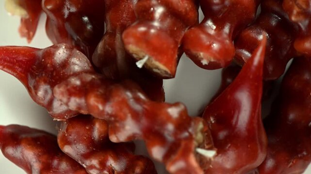 Close up of Churchkhela, a traditional walnut-filled candy, slowly spinning on a turntable. Glossy grape syrup coating, textured walnut interior, and vibrant natural colors captured in high definition