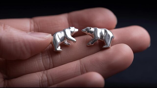 Close-up of Hand Holding Silver Bear Shaped Earrings on Black Background