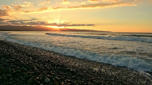 Scenic view of a stunning sunset over the coastline of Cyprus. Warm golden and orange tones reflecting on calm Mediterranean waters, silhouetted shoreline, and soft clouds in the sky. Peaceful and rom