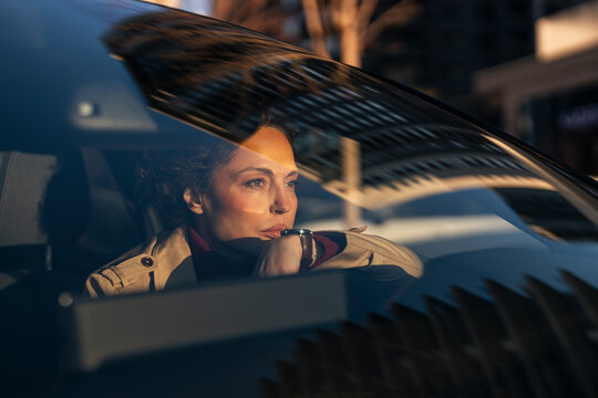 Woman driving car contemplating sunset during evening commute