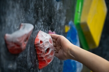 Close Up of a Young Boy Hand Gripping a Red Hold on a Modern Indoor Bouldering Climbing Wall