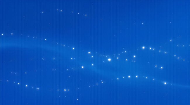 Abstract image of sparkling lights moving across a graduated blue background