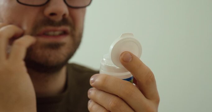 Close-up of a man with visible skin irritation examining medication, highlighting allergic reaction symptoms, itching, and potential adverse drug effects.