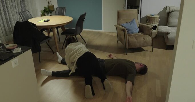 Woman placing an unconscious man into recovery position and calling emergency services, demonstrating first aid response, lifesaving skills, and critical home emergency situation.