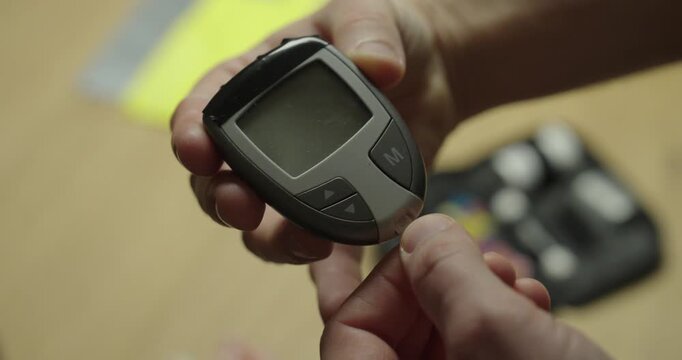 Close up of a person holding a digital glucometer and test strip before measuring blood glucose level, illustrating diabetes monitoring and personal health management.