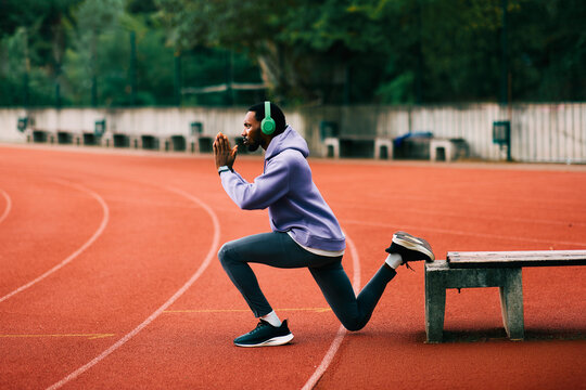 African athlete performing bulgarian split squat on running track