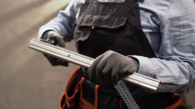 Cutting galvanized metal profile with snips during apartment renovation.