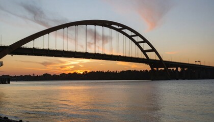Obraz premium Sunset Silhouette - A Modern Bridge Over Calm Waters at Dusk.