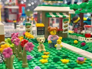 Naklejka premium Lego minifigure family in city park with flowers and dog