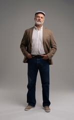 Full length body size view of attractive serious grey-haired man in suit and flat cap isolated on grey