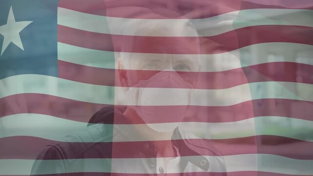 Animation of flag of liberia over senior caucasian man in face mask