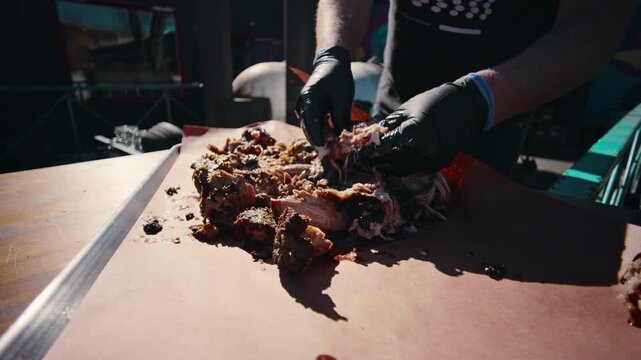 Bird's eye overhead view of shredded pulled pork spread across pink butcher paper in a metal tray with visible charred ends and juices