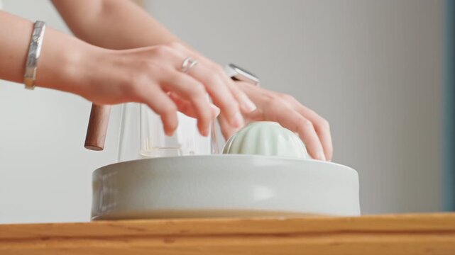 Hands arrange welcome tray in hotel, ceramic dish with glass carafe and soap, gentle touch and minimalist wooden counter, warm light and cozy boutique atmosphere for arriving guest