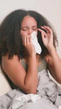 Young Black Woman With Natural Hair Sneezing And Blowing Her Nose In Bed
