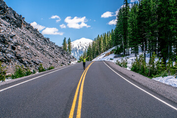 A person is walking on a road with a mountain in the background