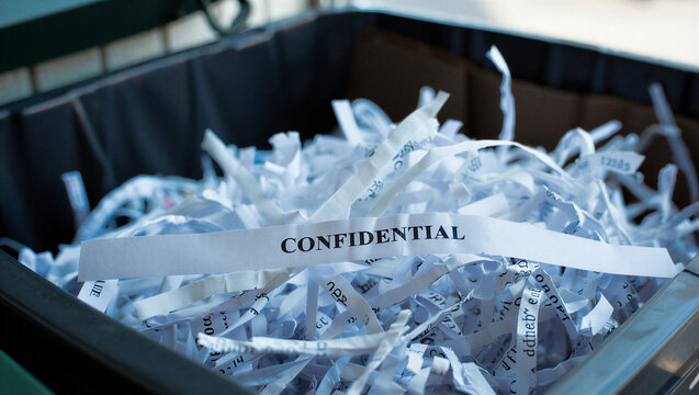Shredded confidential paper filling a waste bin highlights the importance of data protection and privacy.