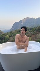 Luxury Wellness Retreat in Thailand: Handsome Man in Bathtub Overlooking Scenic Valley During Golden Hour