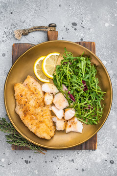 Crispy fried redfish fillet with green salad and citrus. Balanced seafood dinner plate.