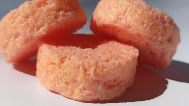 Soft sponge snack with strawberry flavor and pink layers, a sweet treat often found in bakeries and snack stalls with a light texture and fruity aroma