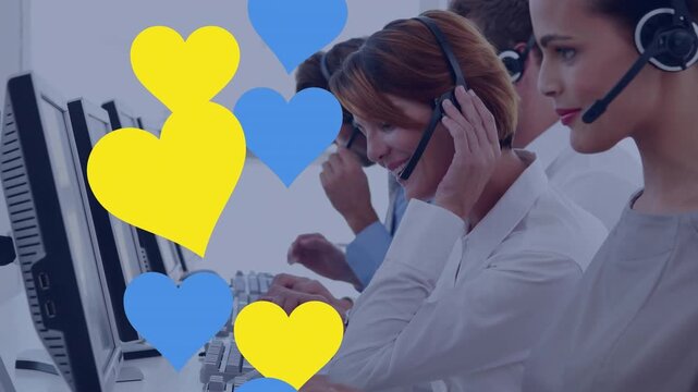 Multiple blue and yellow heart icons against team of diverse customer care executives working