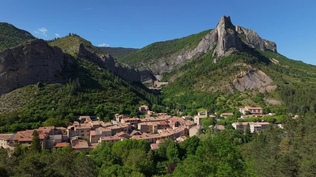 The medieval Provence village of Orpierre nestles at the foot of a steep cliff in Baronnies Provencales (aerial view). Summer in Hautes-Alpes, French Alps, France