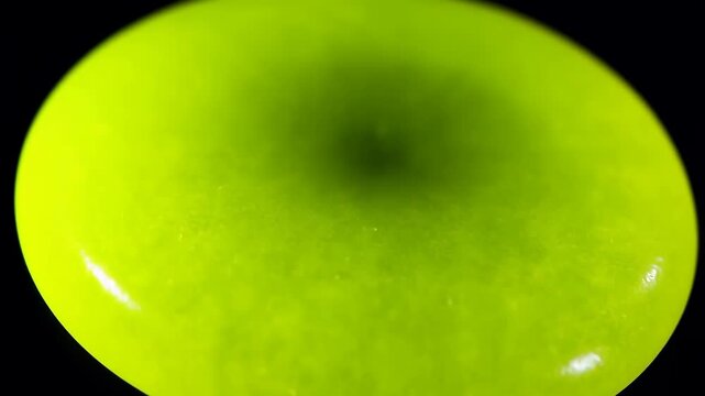 Bright neon green liquid torus shape forming in slow motion with a dark background, abstract fluid dynamics, vibrant chemical reaction
