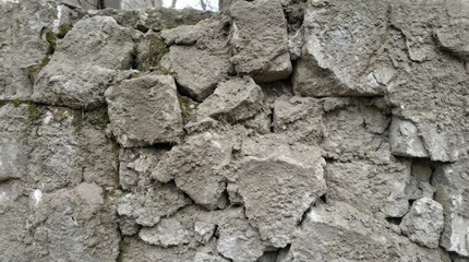 Close-up view of a weathered concrete wall with rough, uneven fragments and textures