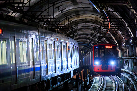 Fukuoka Japan - 2021 June 09: A JR Kyushu 303 series train runs on the curved tracks inside a dimly lit underground tunnel of the Fukuoka City Subway,