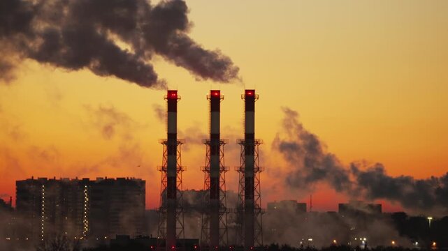 Industrial Smokestacks Emitting Smoke Over City at Sunrise