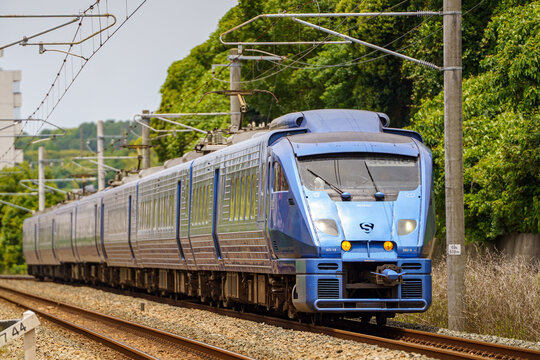 Fukuoka, Japan - 2025 June 06: A JR Kyushu 883 series limited express train "Sonic" (AO-18 set) runs on the curved tracks. The train features a distinctive metallic blue body.