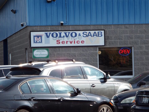 Ottawa, Ontario, Canada-July 17, 2025: A storefront sign for "Volvo and Saab service" is displayed on a grey brick building on Hunt Club Rd.
