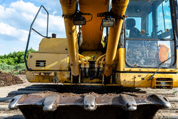 Fototapeta premium Yellow excavator bucket and cabin showing heavy construction equipment