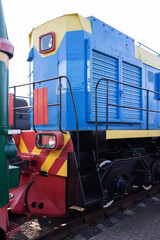 Colorful blue and yellow locomotive on railway tracks in an industrial setting during daytime