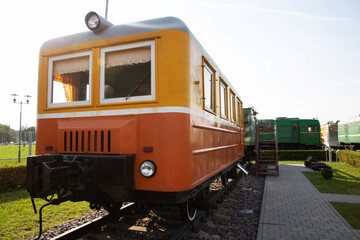 Obraz premium Historic orange and cream railcar displayed at an outdoor museum on a sunny day in a park setting