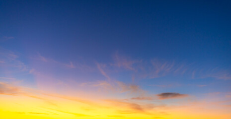 Golden Wispy Clouds at Sunset in Blue Twilight Sky,A panoramic view of vibrant orange and yellow...