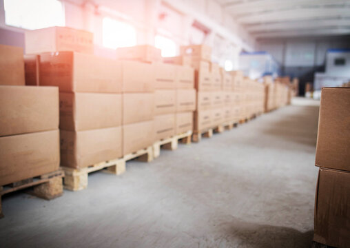 Large warehouse interior with rows of stacked cardboard boxes on wooden pallets, concept of storage and logistics operations. Copy space for text