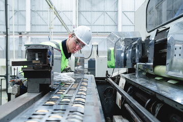 Caucasian technician leaning over conveyor production system inspecting packaging items in...