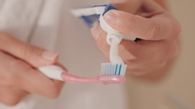 Guest brushes teeth. Hotel guest brushes teeth quickly. Person prepares toothbrush and toothpaste for morning routine. Guest in hotel gets ready by brushing teeth with bathroom background