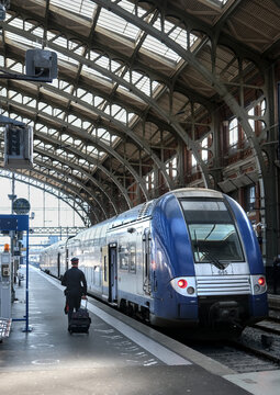 SNCF train driver walks along platform to take duty on a regional train inside a historic railway station in France.